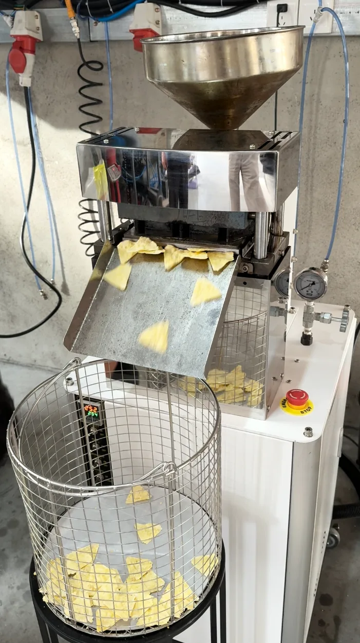 Machine forming triangular corn chips above a collection basket